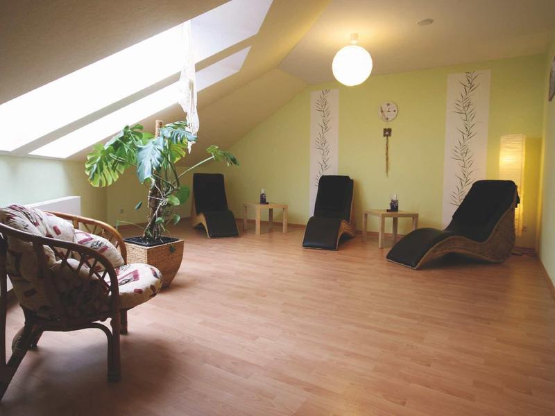 Przytulny pokój relaksacyjny z drewnianą podłogą, leżakami i dużymi świetlikami pod dachem.