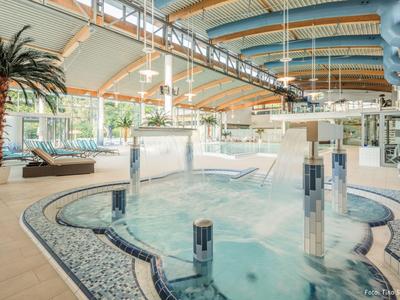 Moderner Indoor-Poolbereich mit Massagedüsen und Palmen in einem Hotel.