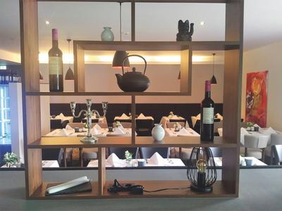 Moderner Holzbarschrank mit Weinflaschen, Keramikvasen und dekorativen Objekten im Restaurant.