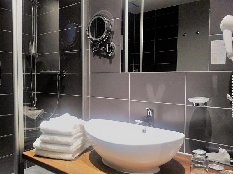 Modern bathroom with round sink, stacked towels, and large mirror.