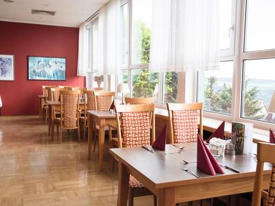 Helles Restaurant mit Holzmöbeln und großen Fenstern mit Meeresblick.