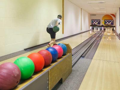 Ein Mann bereitet sich auf einen Bowlingwurf in einer modernen Bowlingbahn vor.
