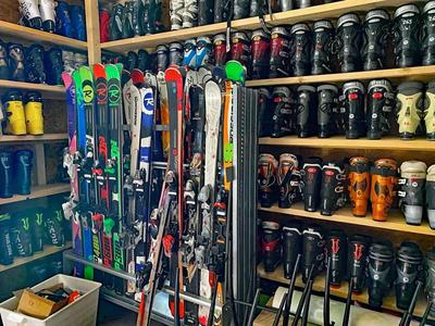 Regal mit vielen Skischuhen und Skiern in einem Geschäft oder Lagerraum.