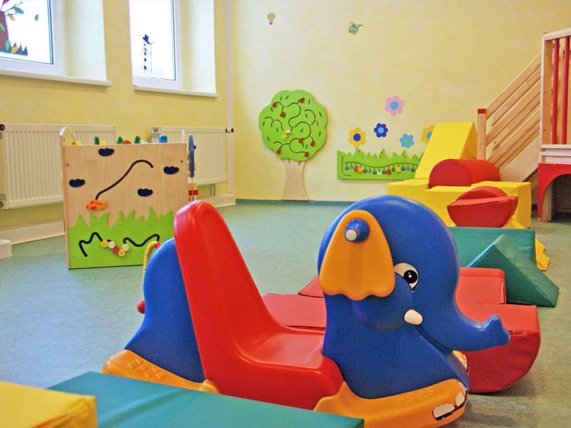 Buntes, kinderfreundliches Zimmer mit Elefanten-Rutschbahn und weichen Spielpolstern.
