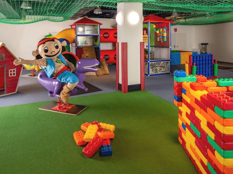 Salle de jeux colorée pour enfants avec de grands blocs de construction et une figure enfantine joyeuse.