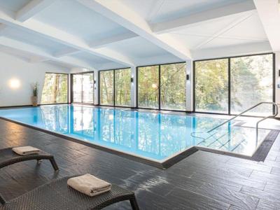 Indoor pool with glass windows, sun loungers, and modern design in a wellness area.