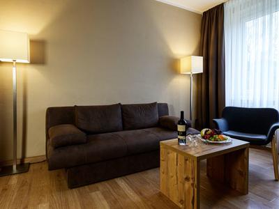 Cozy living room with brown sofa, wooden coffee table, and a window with curtains.