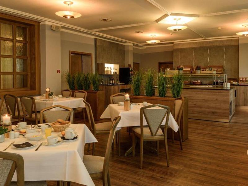 Elegant restaurant with set tables, wooden chairs, and plants as decor.