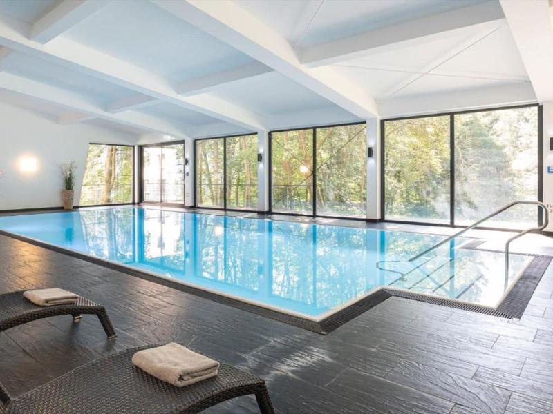 Indoor pool with glass windows, sun loungers, and modern design in a wellness area.