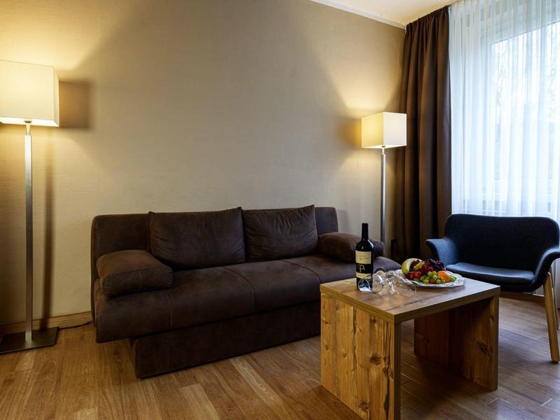 Cozy living room with brown sofa, wooden coffee table, and a window with curtains.