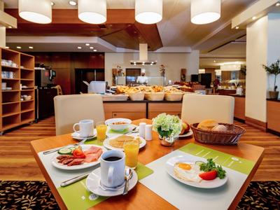 Ein gedeckter Frühstückstisch mit Kaffee, Eiern, Wurst und Brot in einem Hotelrestaurant.