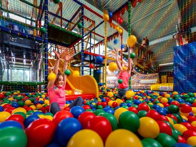 Kinder spielen in einem großen Bällebad mit bunten Plastikbällen in einer Indoor-Spielhalle.