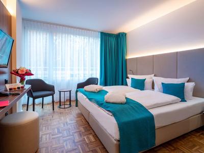 Modernes Hotelzimmer mit Doppelbett, blauen Akzenten und gemütlicher Atmosphäre.