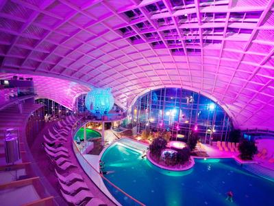 Indoor-Poolbereich eines Hotels mit bunter Beleuchtung und modernen Sitzgelegenheiten.