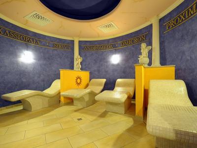 Sala relax circolare con lettini e pareti decorate in blu e giallo.