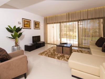 Living room with sofa, armchair, flat-screen TV, and large window with curtains.