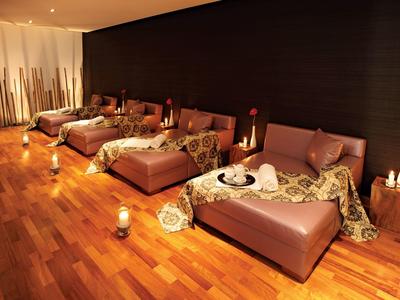 A relaxing spa room with brown loungers, warm wooden floors, and soft lighting.