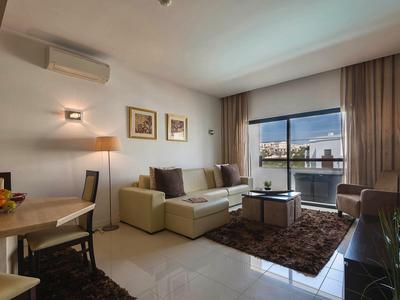 Modern living room with sofa, armchairs, and large window overlooking the city.