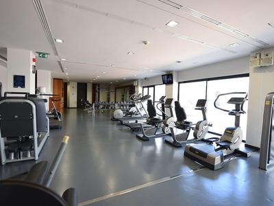 Großer Fitnessraum mit modernen Geräten und großen Fenstern in einem Hotel