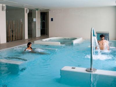 Indoor pool with two people relaxing in a hotel wellness area.