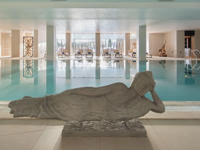 Large indoor pool with stylish reclining statue in a relaxed atmosphere.