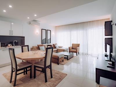 Bright living room with dining area, kitchenette, and large window with curtains.