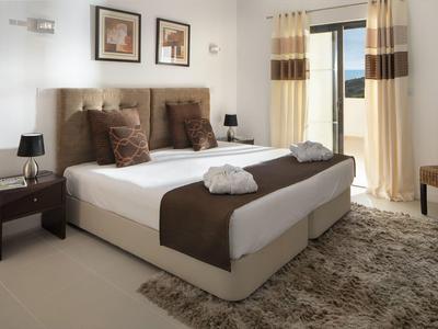 Modern hotel room with double bed, brown accents, and carpeted floor.