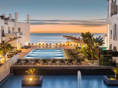 Hotel with illuminated pool and sea view at sunset