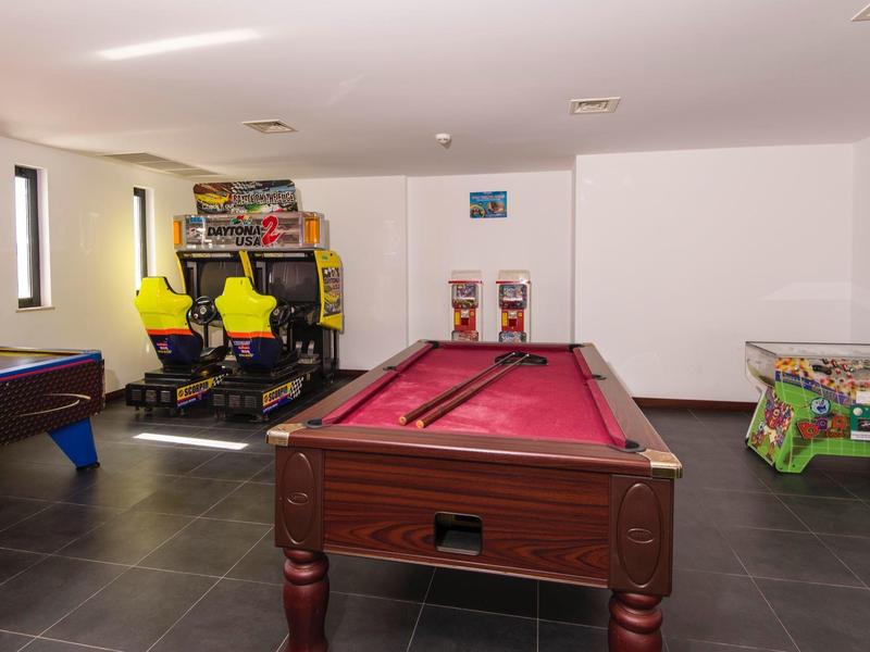 Recreation room with billiards table, arcade games, and air hockey tables.