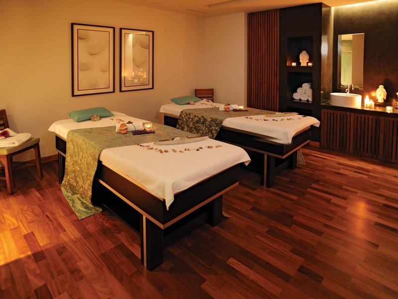 Cozy spa room with two massage tables and dim lighting.