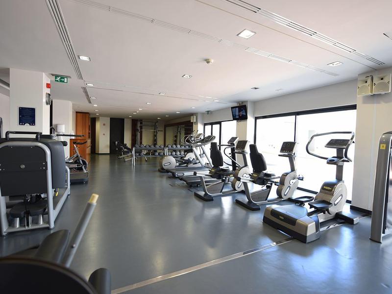 Modern gym room with various exercise machines and large windows