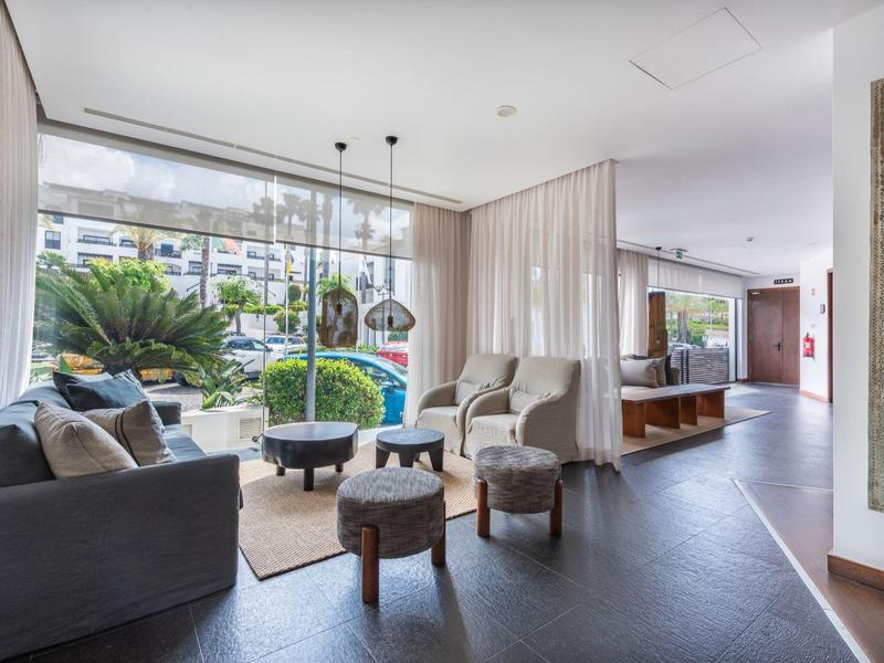 Modern hotel lobby with seating areas, large windows, and bright interior design.