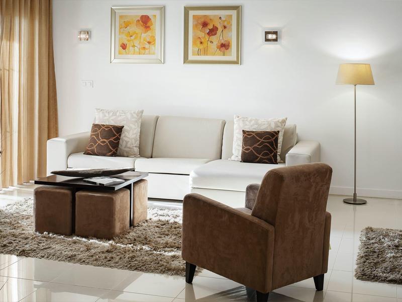 Bright living room with white sofa, brown armchair, rug, and modern decorations.