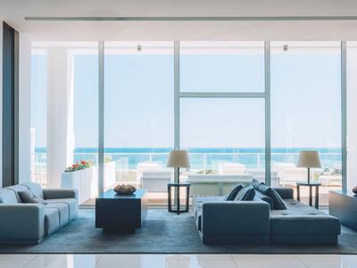 Moderner Wohnraum mit großem Glasfenster, Blick aufs Meer, graue Sofas und dezente Deko.