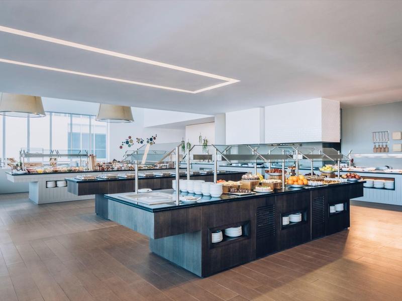 Jasna, nowoczesna restauracja z bufetem, różnorodne potrawy i duże okna.