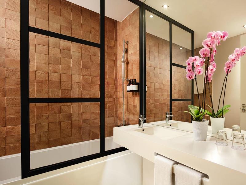 Moderne badkamer met wastafel, spiegel en orchideeën op het aanrecht.