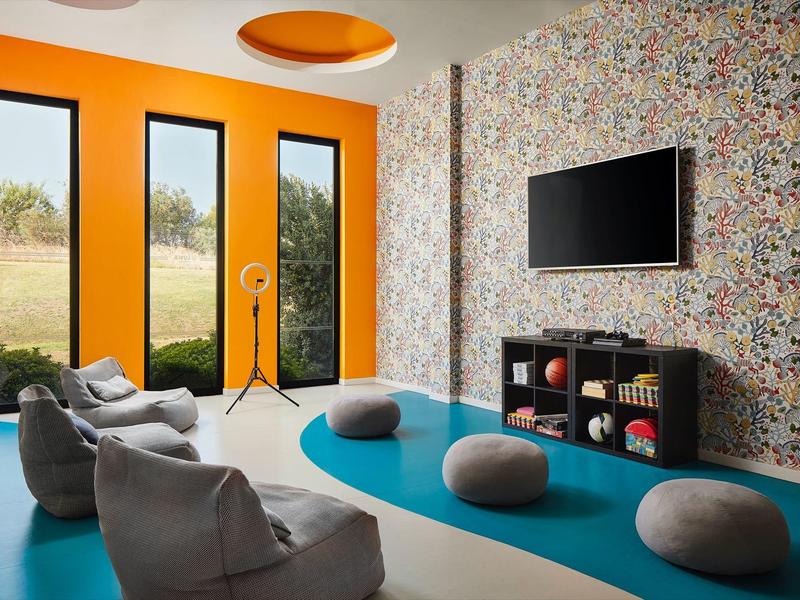 Moderne lounge met kleurrijk tapijt, comfortabele fauteuils en wand-tv.