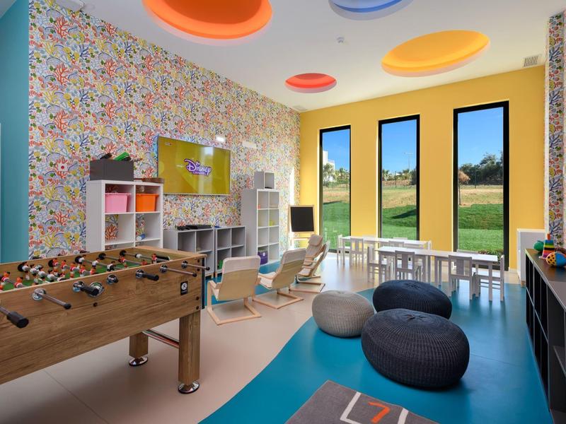 Kleurrijke speelkamer met tafelvoetbal, zitzakken en grote ramen met uitzicht op groen landschap.