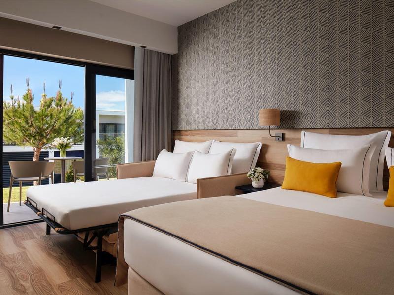 Modern hotelkamer met twee bedden, balkon en uitzicht op de tuin.