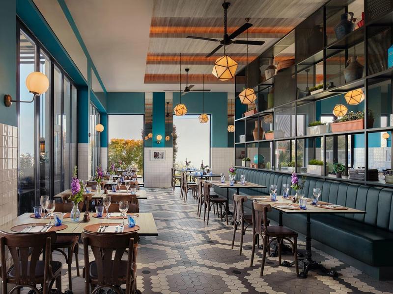 Modern restaurant met blauwgroene muren en elegante houten meubels.