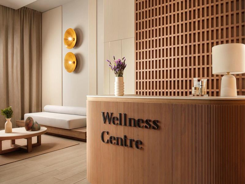 Moderne wellnessruimte met een receptiebalie, bank en warme houten accenten.