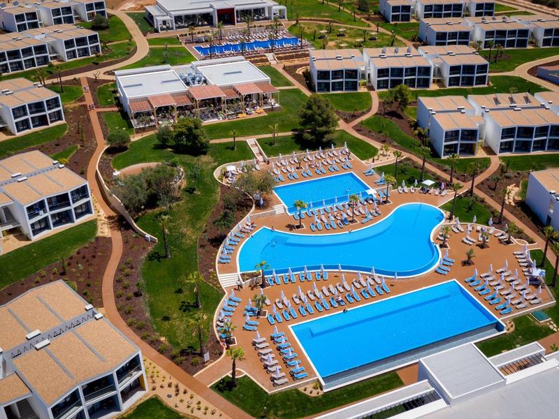 Luchtfoto van een resort met grote zwembaden en omliggende gebouwen.