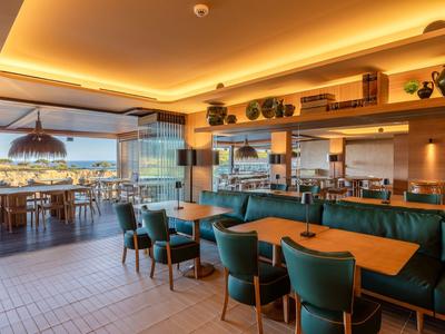 Restaurant moderne avec des zones de sièges confortables et une terrasse avec vue sur la mer.