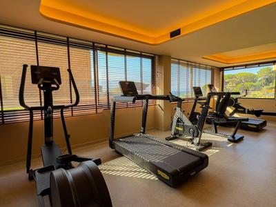 Modernes Fitnessstudio mit Laufbändern und Ergometern, großem Fenster bietet Ausblick.