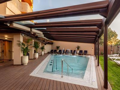 Moderner Poolbereich mit Holzdeck und Sitzgelegenheiten in einem Hotel