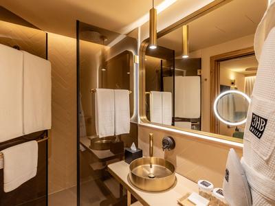 Moderner Hotelbadezimmer mit Glasdusche, rundem Waschbecken und Bademantel am Haken.