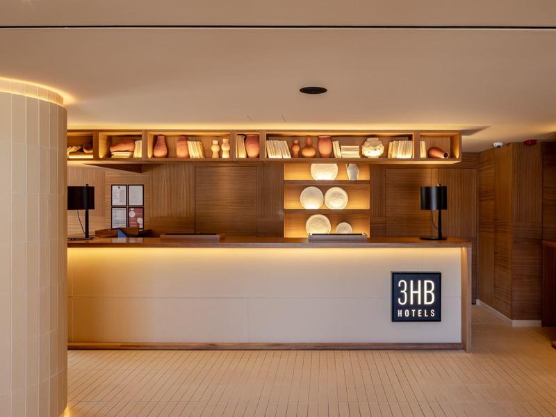 Réception d'hôtel moderne avec comptoir éclairé et étagères décoratives.