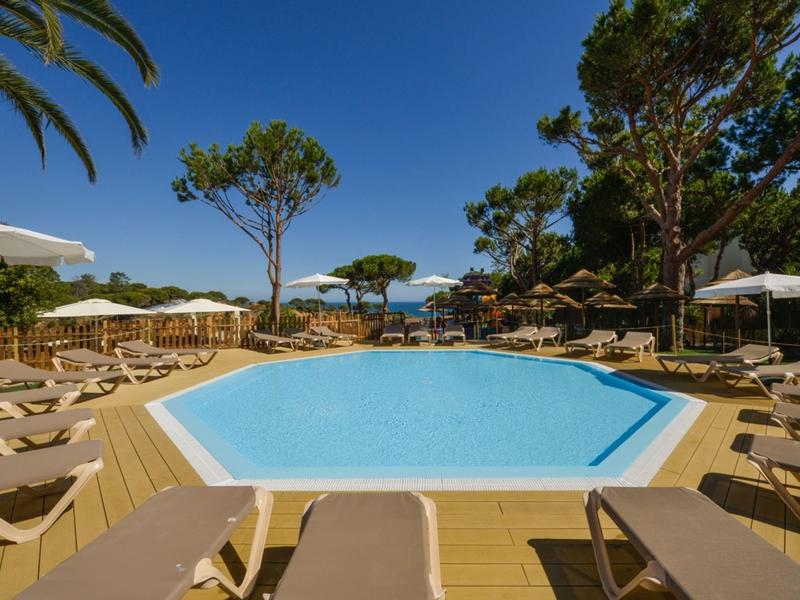 Espace piscine avec chaises longues et parasols dans un hôtel tropical