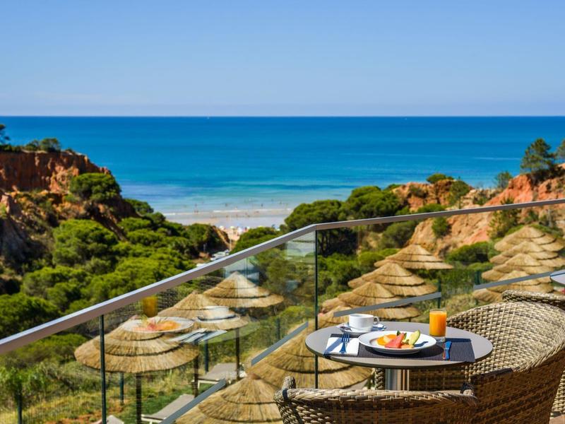 Balcon avec table et petit-déjeuner avec vue sur la plage et la mer sous un ciel clair.