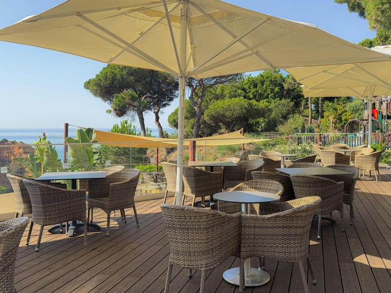 Terrasse avec tables et chaises sous de grands parasols avec vue sur la mer